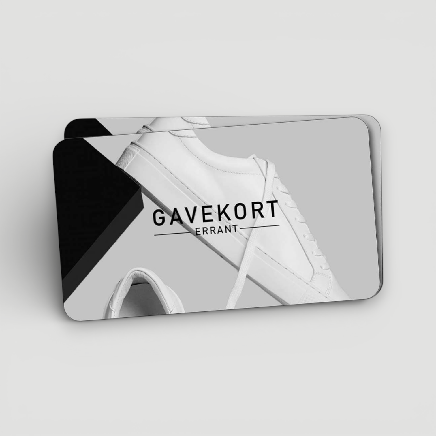 Billedet viser to gavekort med et minimalistisk design. På gavekortene er der et billede af en hvid sneaker og teksten "GAVEKORT ERRANT" i sort skrift. Baggrunden er grå og sort.