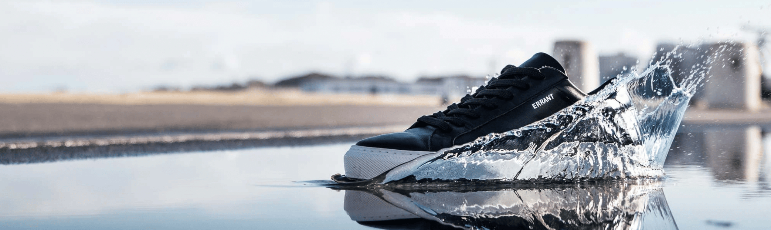 Sort sneaker sprøjter vand på en strandpromenade.