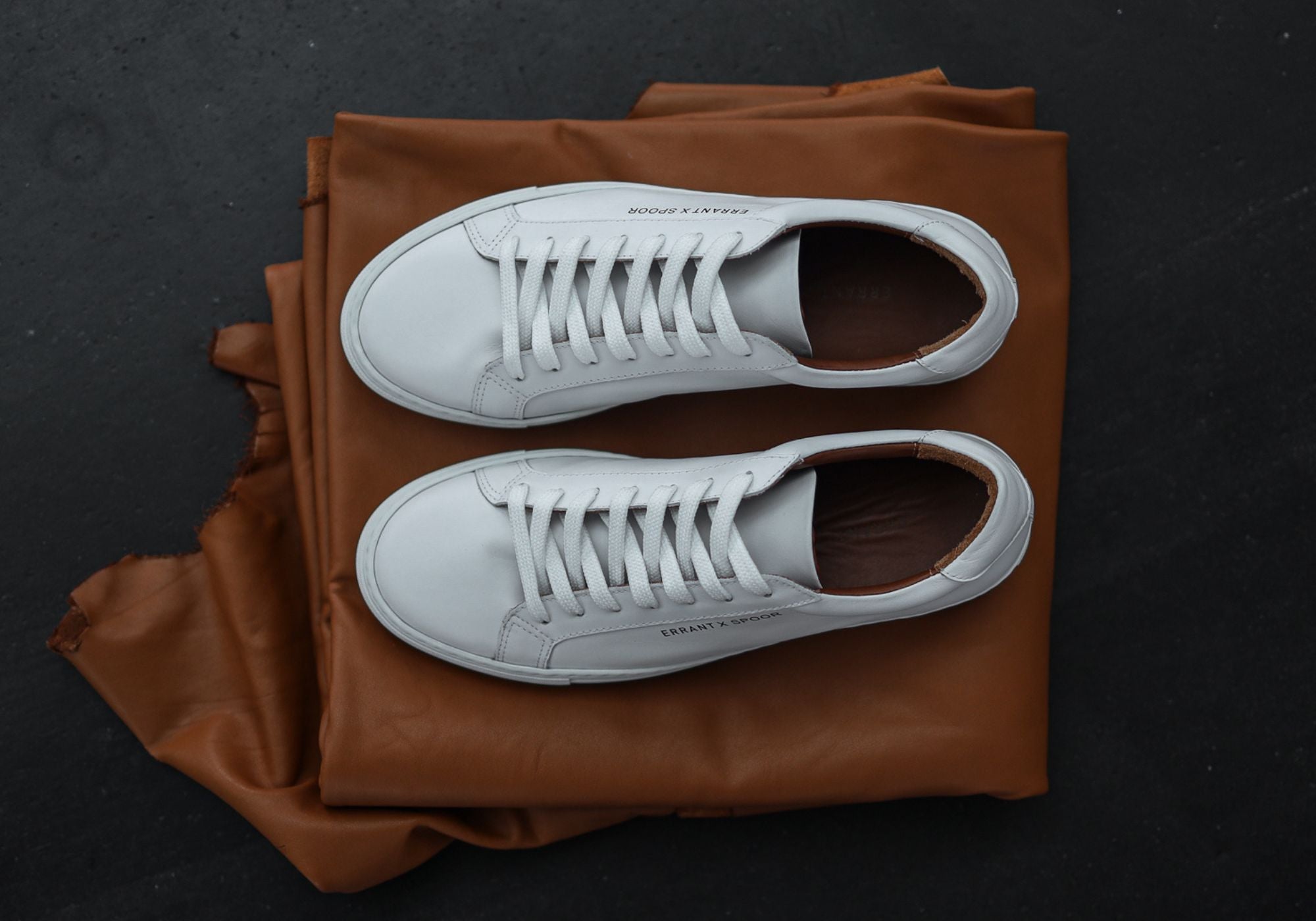 Et par Essential Sneaker - White Classy på et stykke brunt læder 