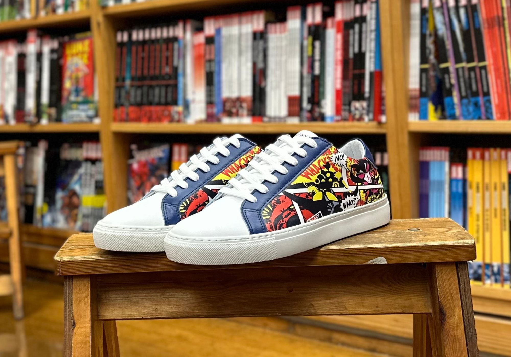 Et par Errant X Fantask Sneakers står på en skammel foran bogreol