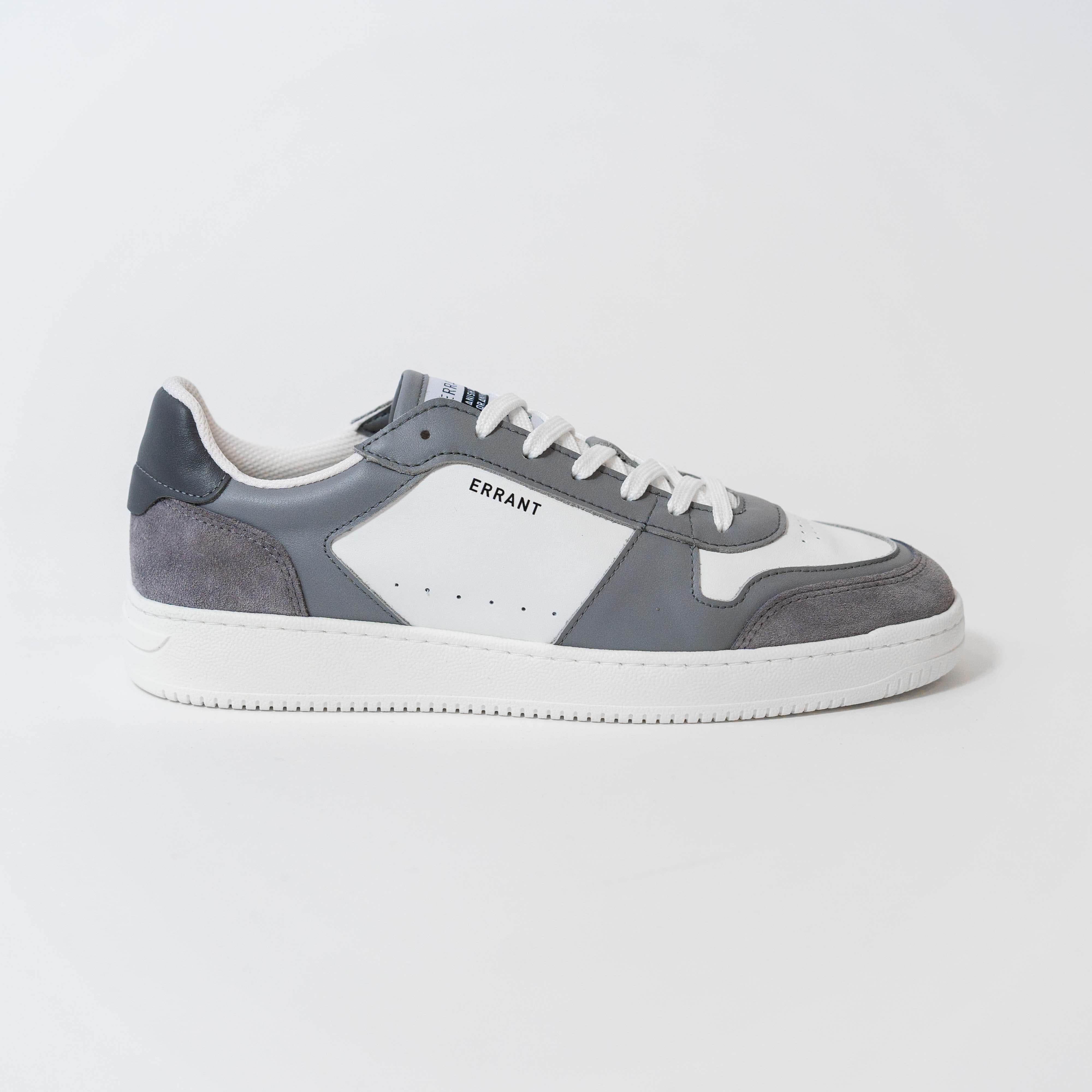 Billedet viser en grå og hvid sneaker fra mærket Errant, set fra siden. Skoen har en hvid sål og grå detaljer på overdelen.