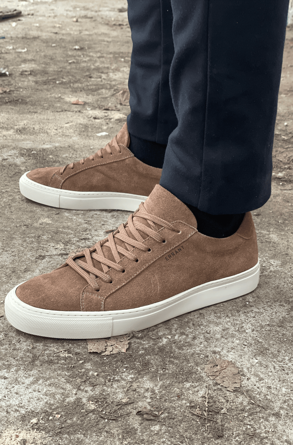 Brune sneakers på en person iført sorte bukser.