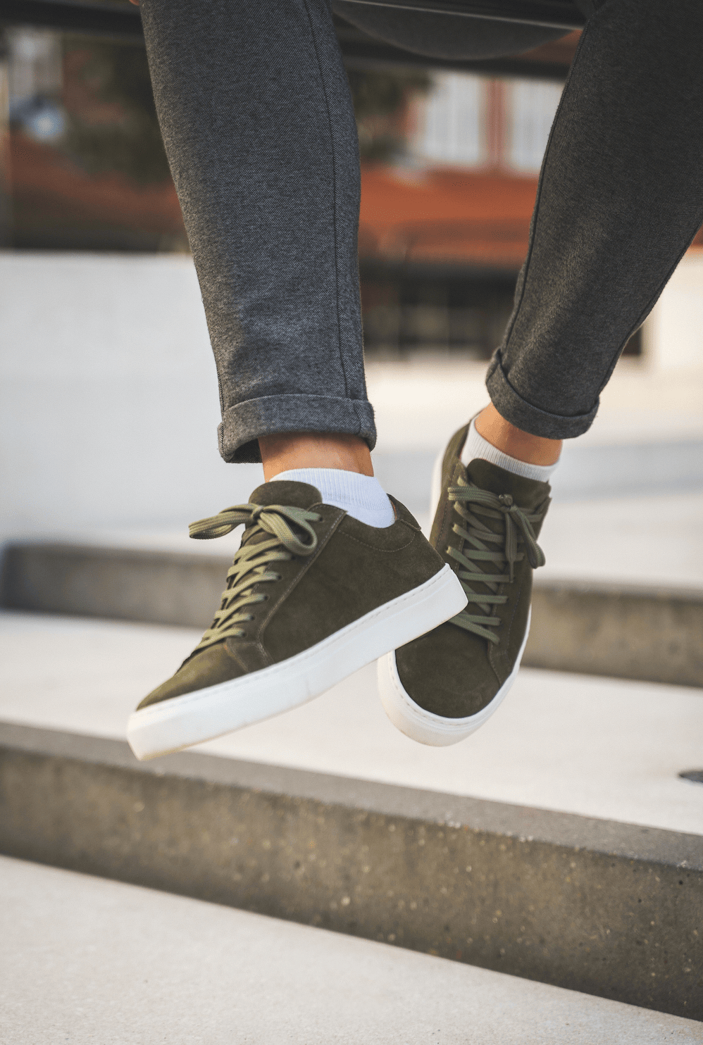 Person iført grønne sneakers og grå bukser.