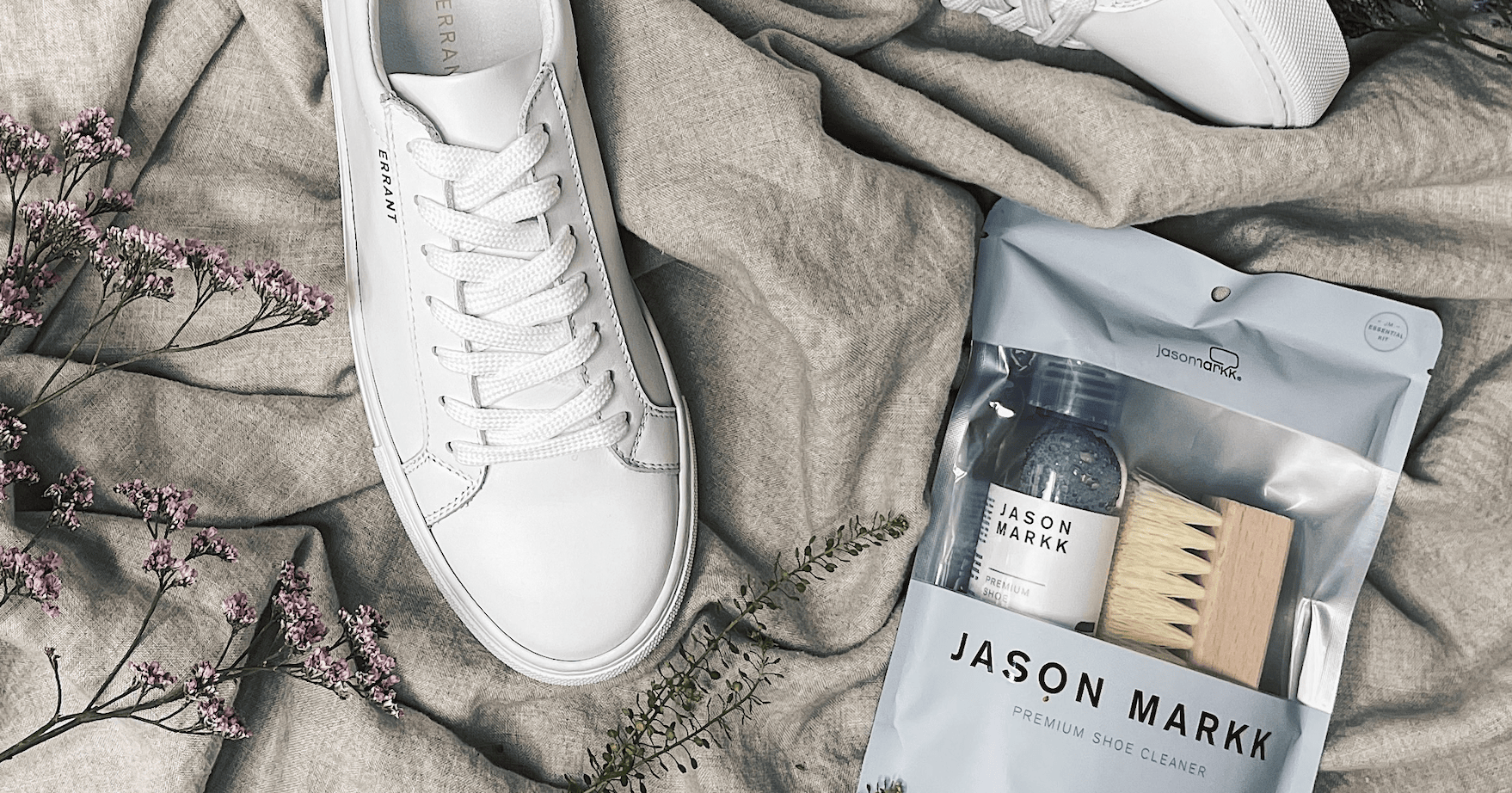 Hvide sneakers og Jason Markk skoplejesæt på gråt stof med blomster.