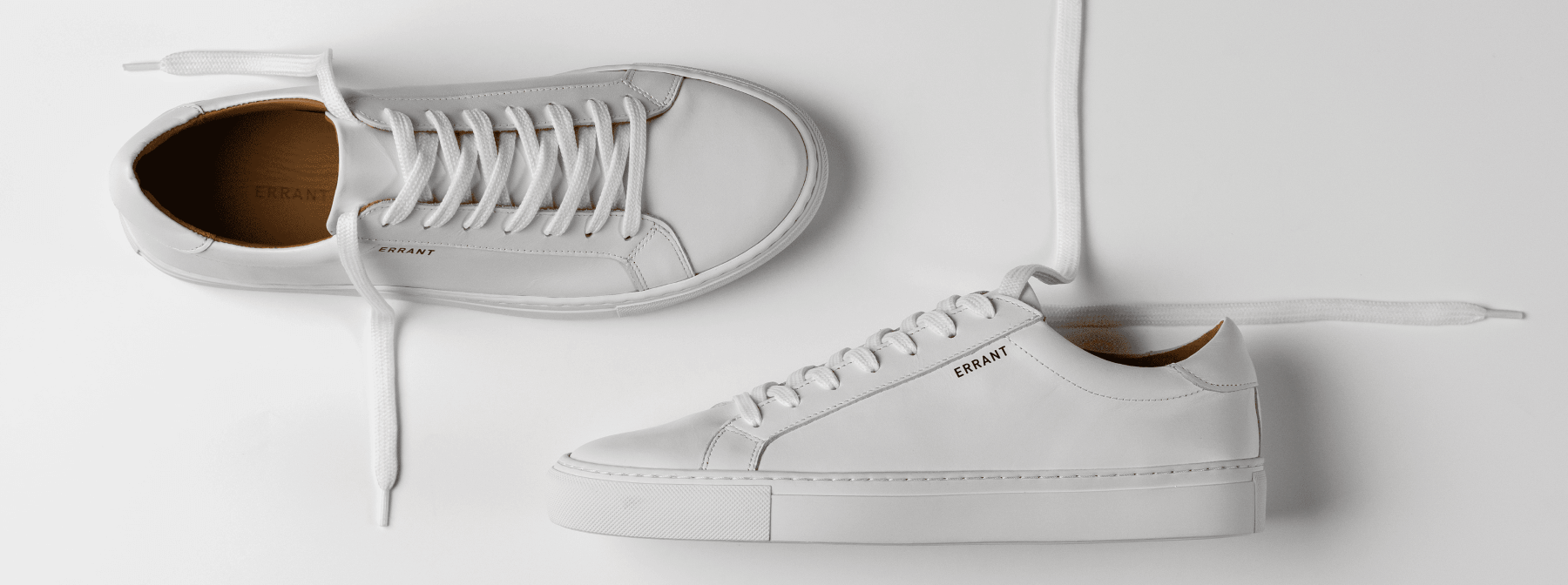 To hvide sneakers med snørebånd på en hvid baggrund.