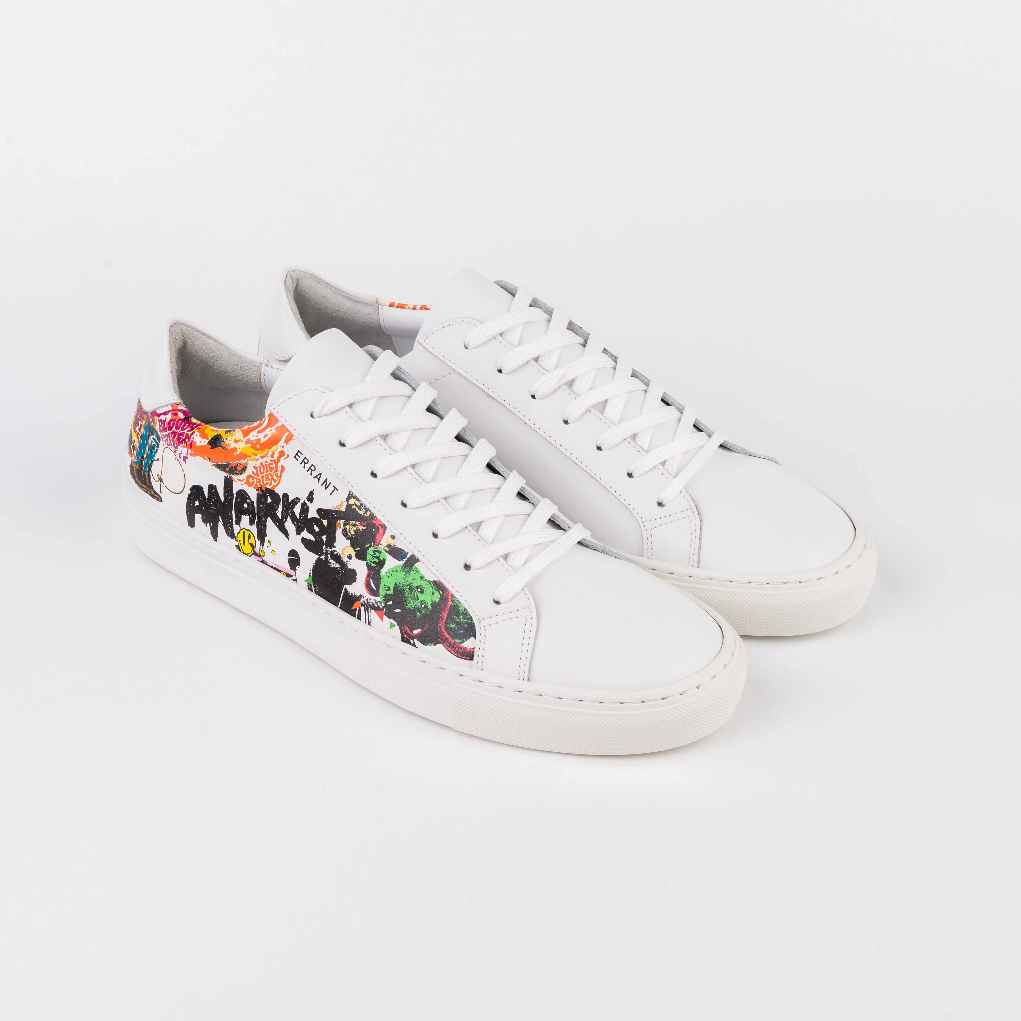 Dette billede viser et par hvide sneakers med farverige graffiti-lignende detaljer og teksten "ANARKIST" på siden.